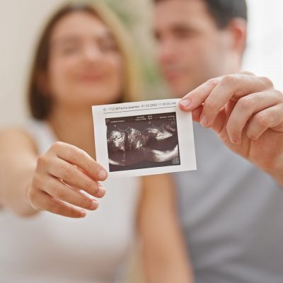 Beautiful couple holding baby ultrasound smiling at bedroom Beautiful couple holding baby ultrasound smiling at bedroom